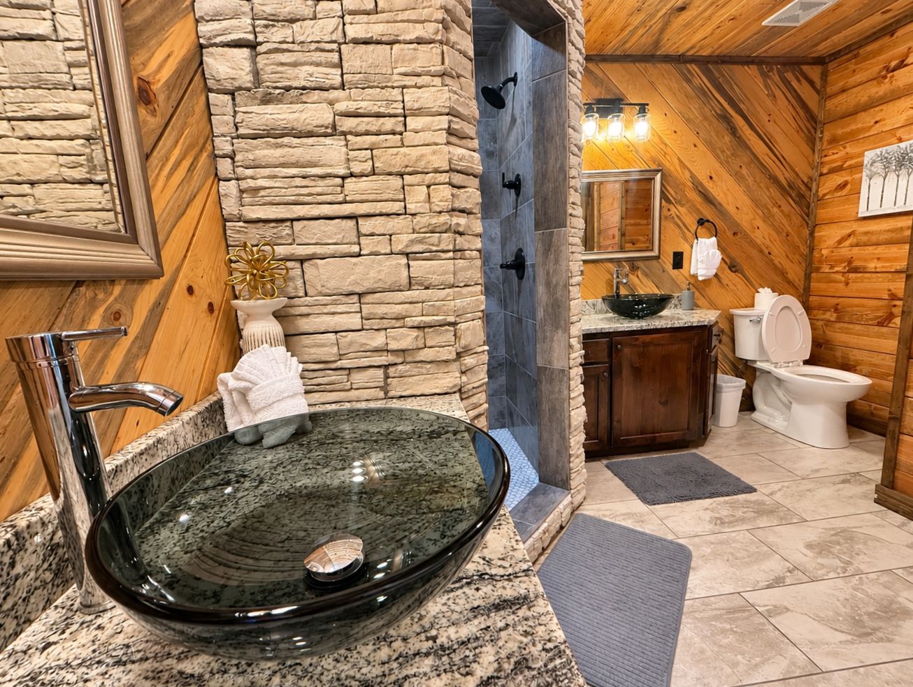 Une salle de bain avec un lavabo en verre, un mur en pierre, un lambris en bois, un miroir et des toilettes.