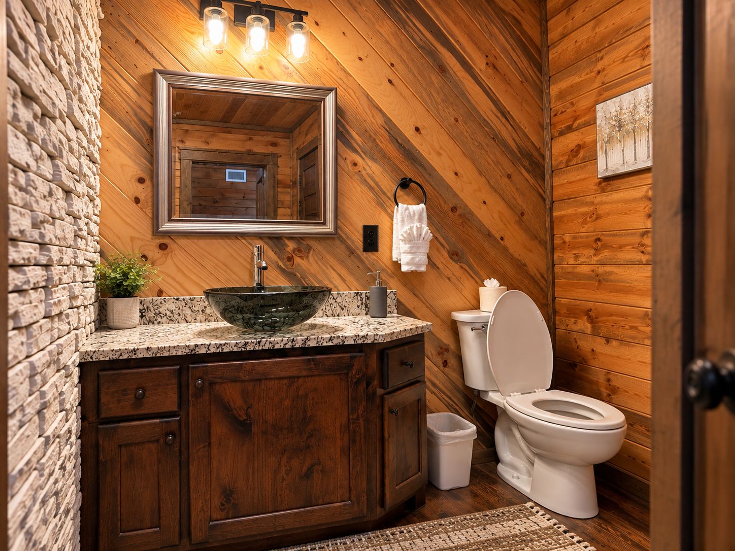 Un bagno con parete in pietra, rivestimento in legno, uno specchio grande, un lavabo a incasso e un water.
