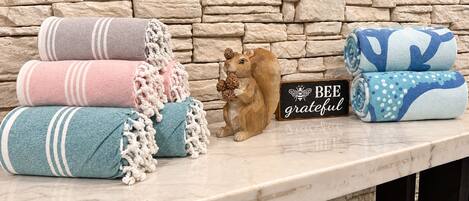 Un muro de piedra con un letrero de madera que dice 'BEE grateful' y una pequeña figura de un oso sosteniendo una piña.