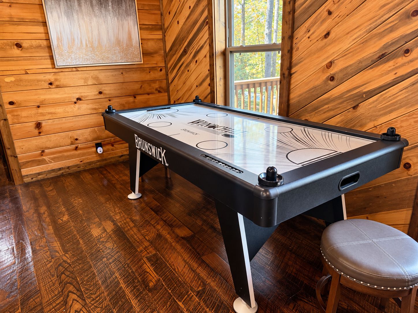 Een Brunswick biljart tafel in een houten kamer met een raam.
