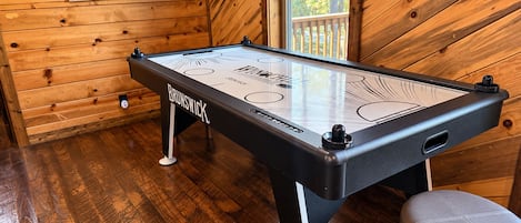 A Brunswick pool table in a wooden room with a window.