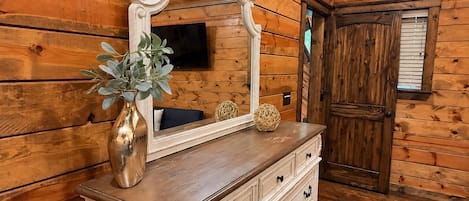 Un interior de madera con un aparador, un espejo, una planta y una puerta.