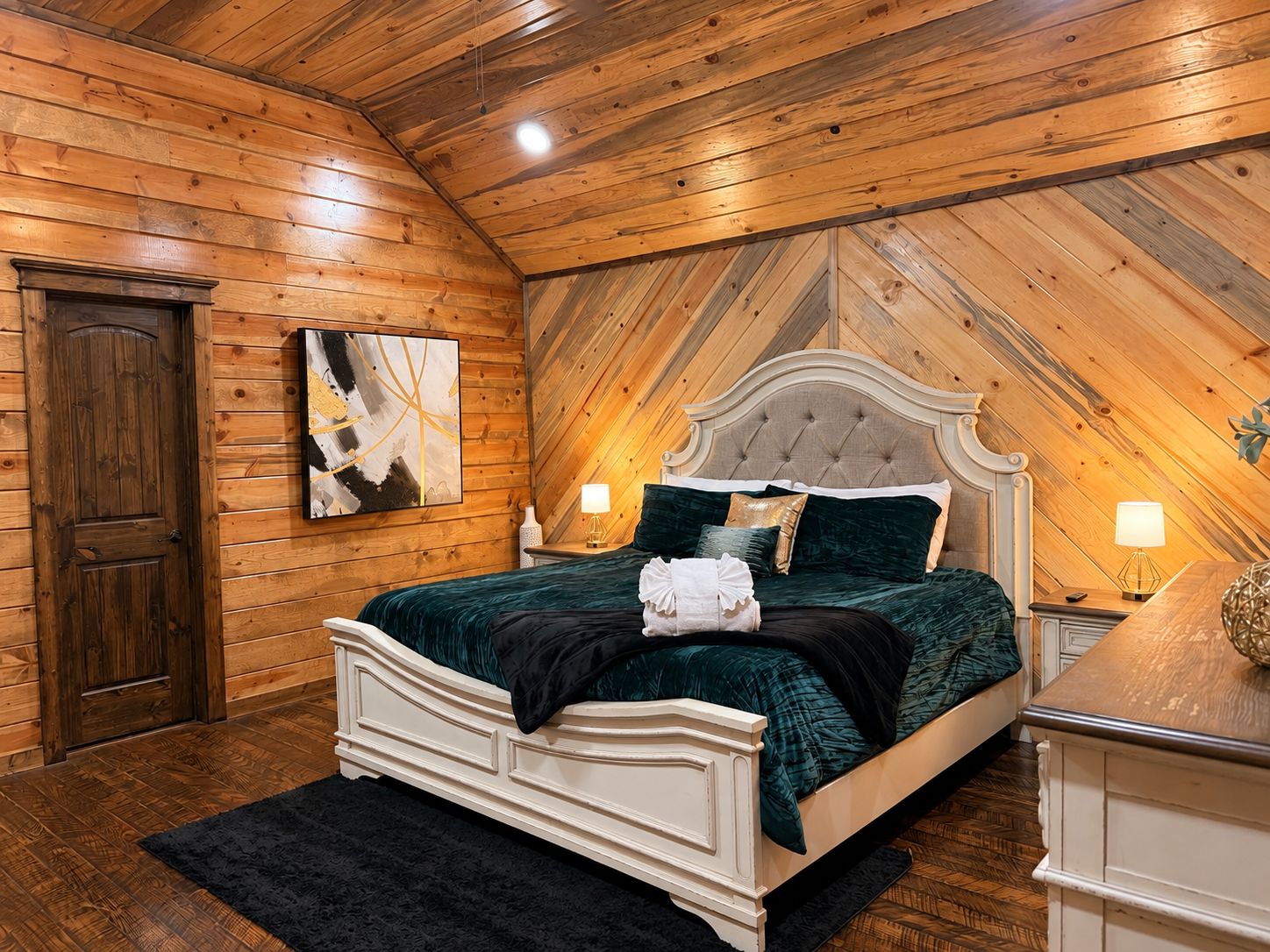 Une chambre avec un plafond en bois, un lit doté d’une tête de lit capitonnée et un tableau accroché au mur.