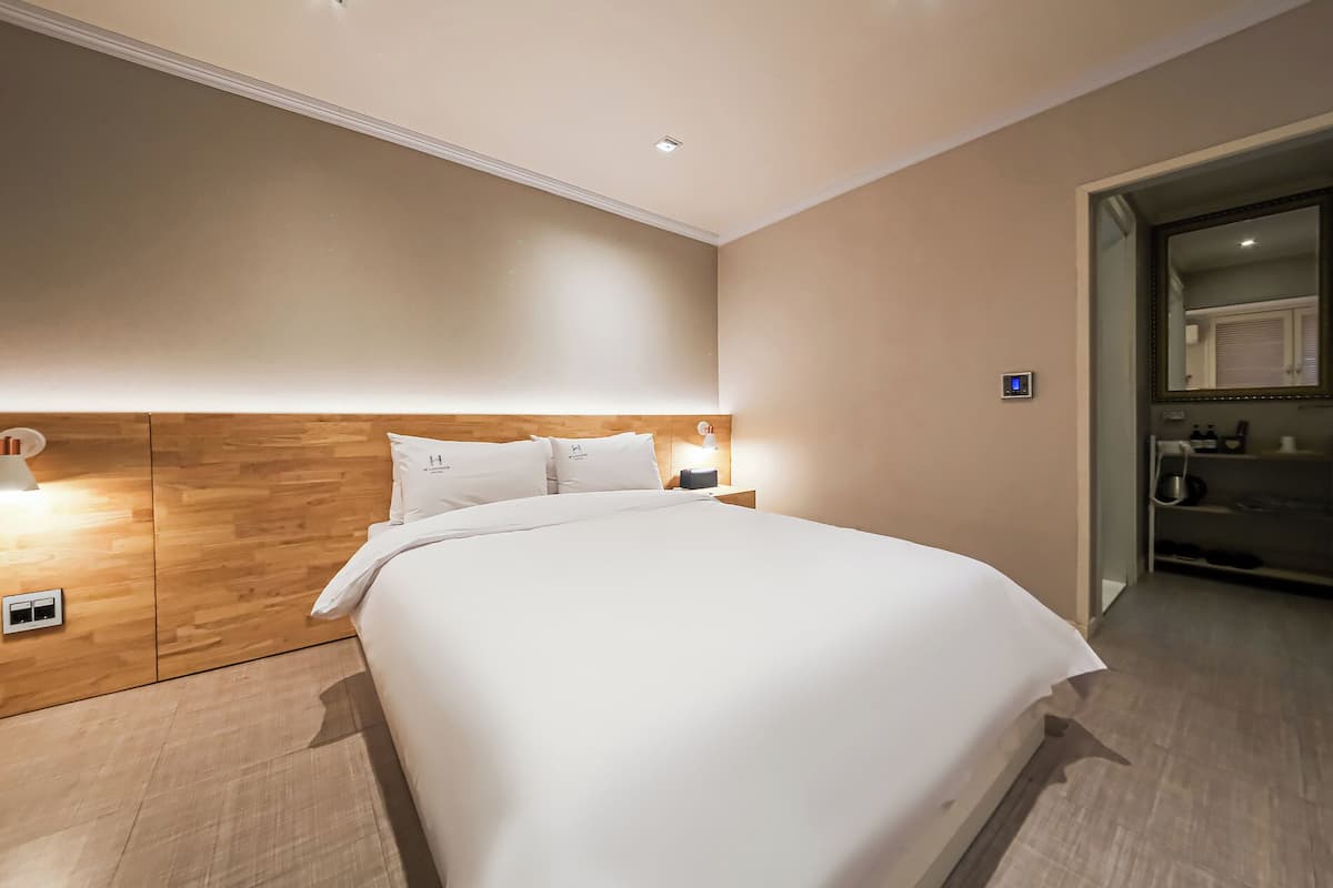 Une chambre d’hôtel avec un grand lit, une tête de lit en bois, des lampes de chevet et une petite table de chevet.