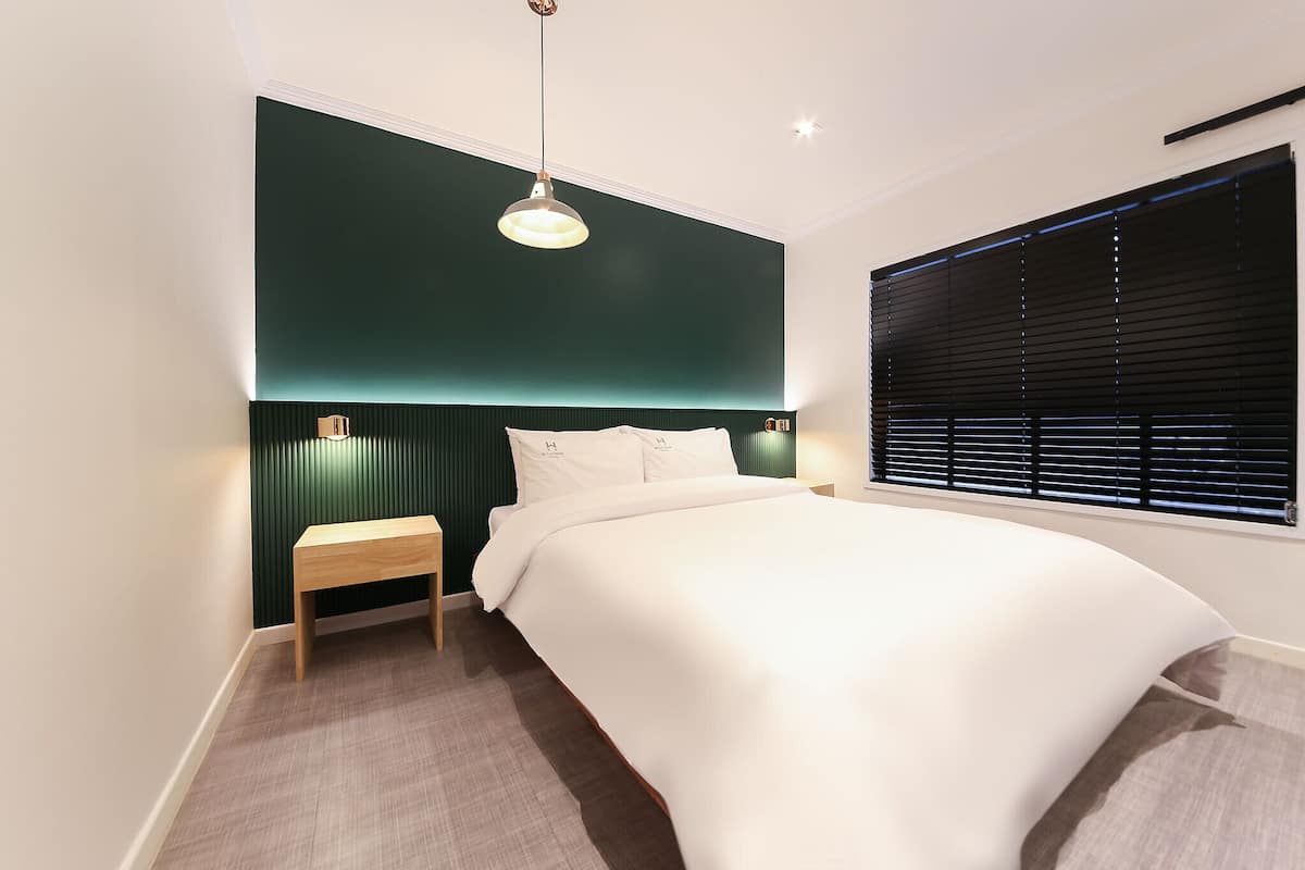 Une chambre à coucher moderne avec un lit, une table de chevet et une fenêtre avec des stores.