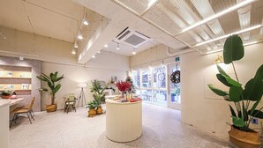 A spacious lobby with a central round table, potted plants, and a seating area with chairs. - Gwangju W Lounge Hotel (Gwangju)