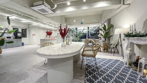 A modern hotel lobby with a central island table, seating area, and decorative plants. - Gwangju W Lounge Hotel (Gwangju)
