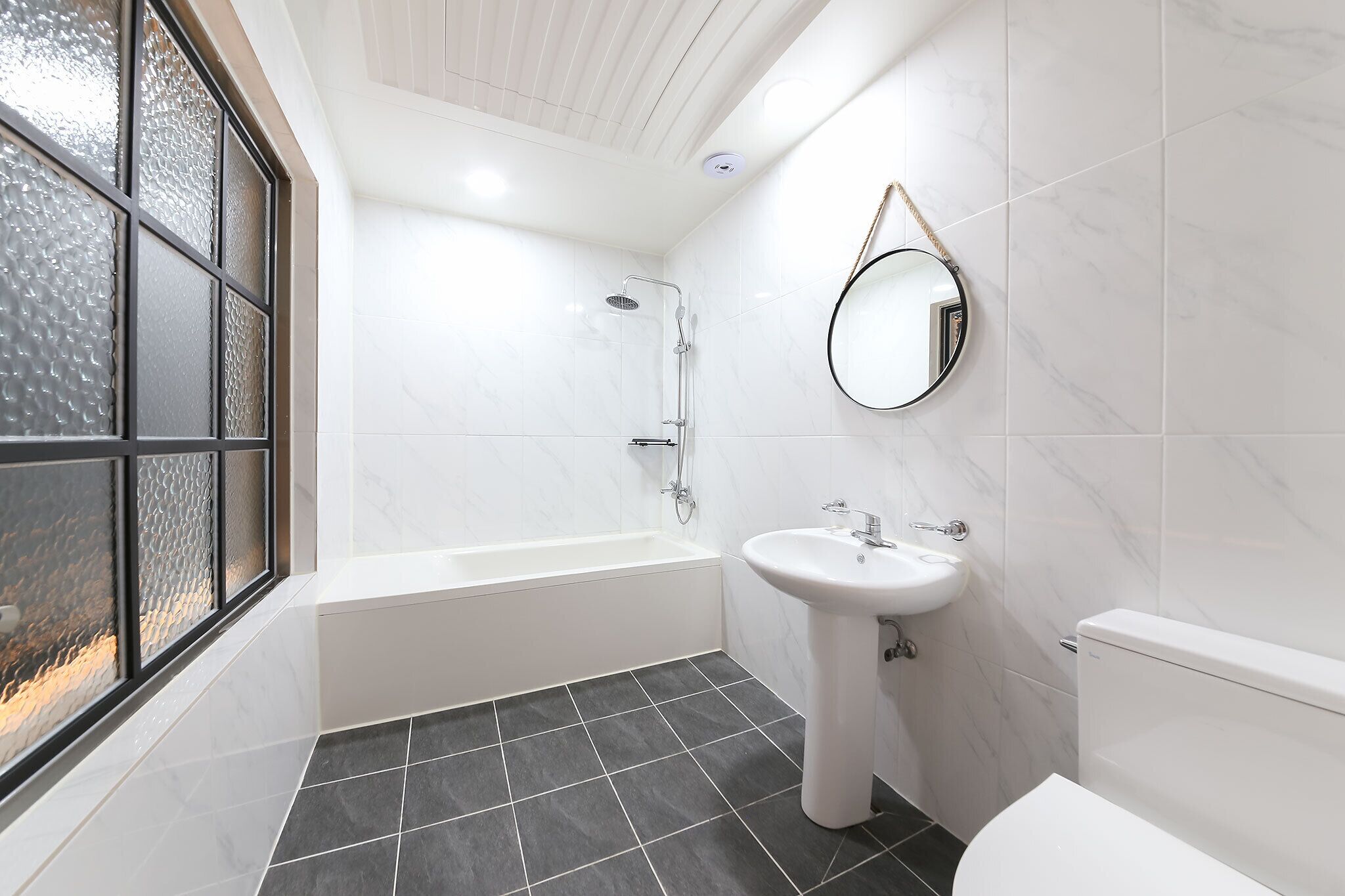 A modern bathroom with a bathtub, sink, and toilet.