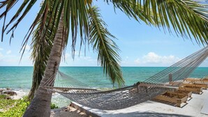 A hammock tied between palm trees on a beach with a view of the ocean. - Ocean Pearl Estate (Nassau)