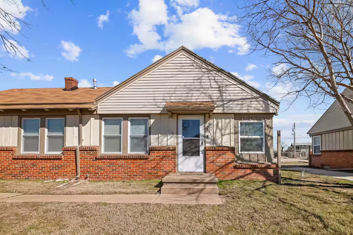 A single-story house with a brick foundation and a gabled roof.