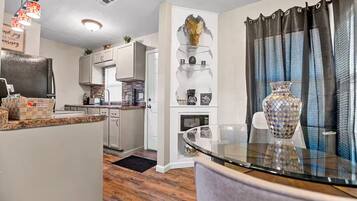 A compact kitchen with white cabinets, a built-in microwave, and a coffee station.