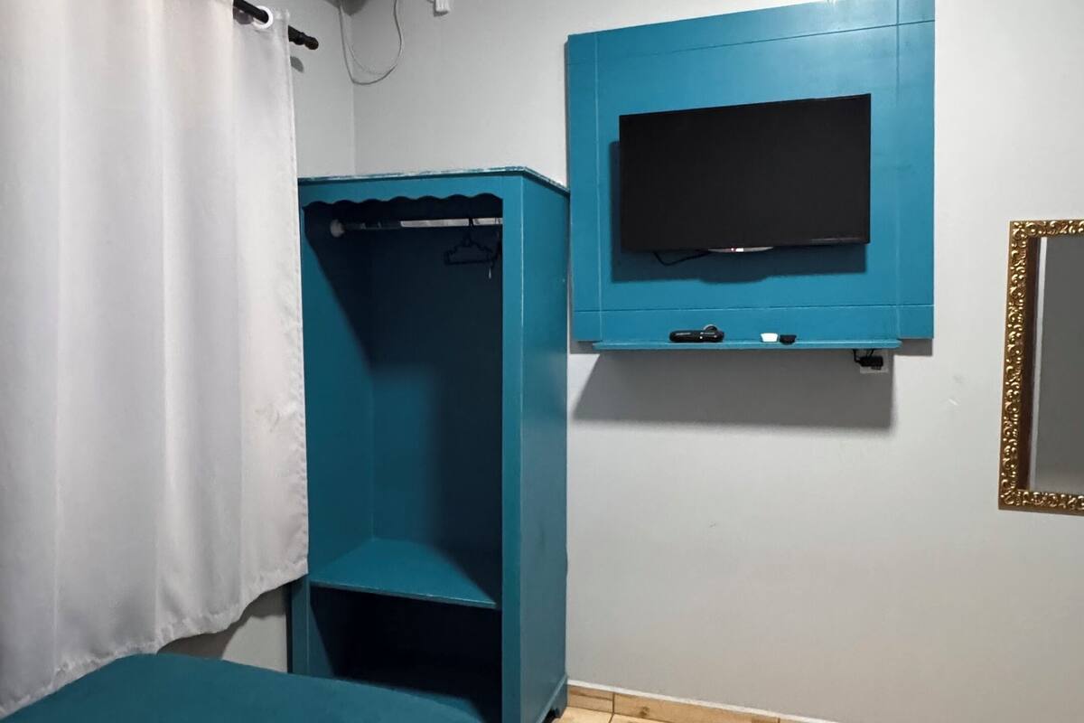 Quarto com duas camas, televisão na parede, ar condicionado e um guarda-roupa.