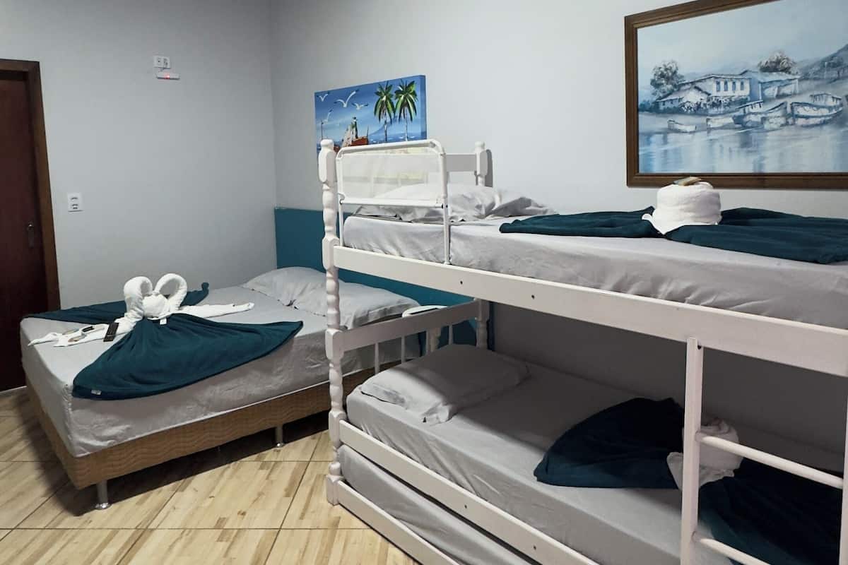 Quarto com beliches, um quadro e piso de madeira.