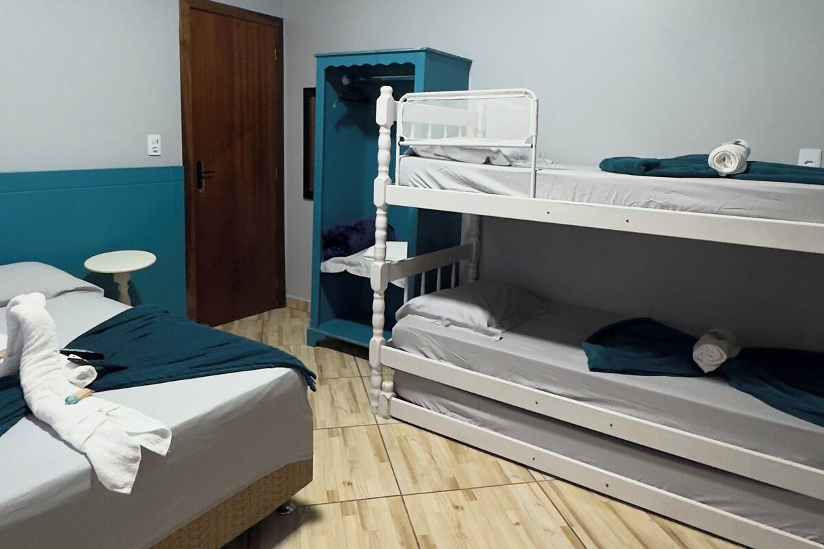 Um quarto com uma cama de solteiro, uma cama individual, piso de madeira, uma porta e uma pequena mesa.