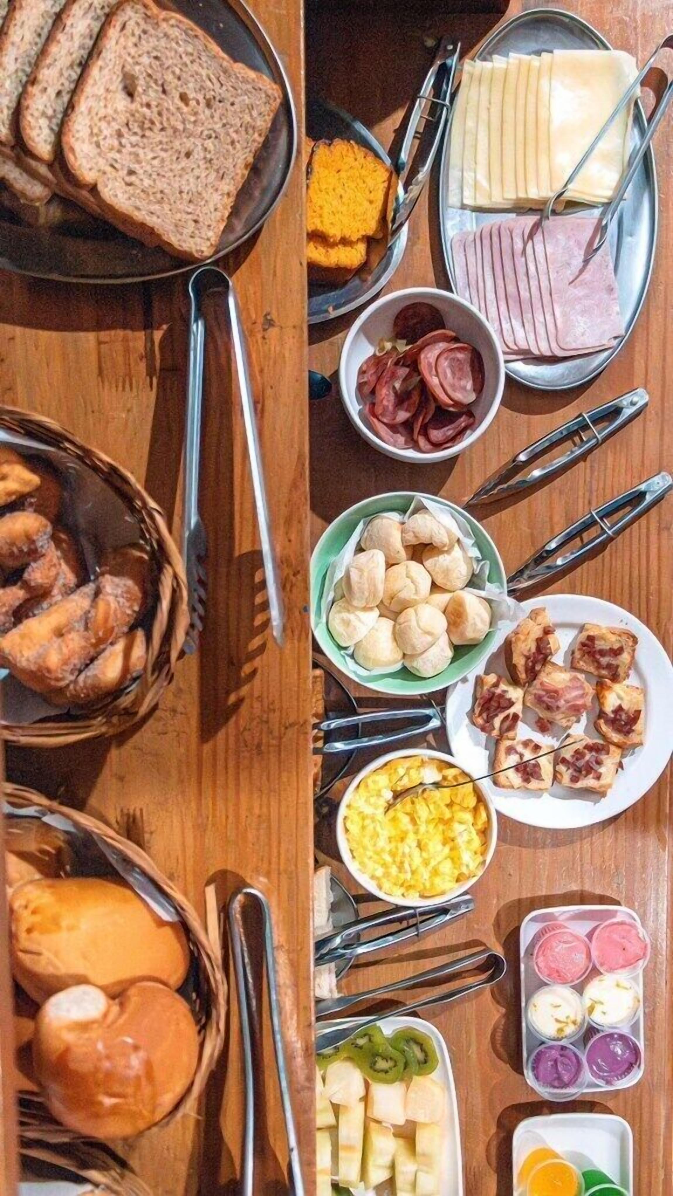Une table garnie de divers aliments, notamment du pain, du fromage, du jambon et des pâtisseries.
