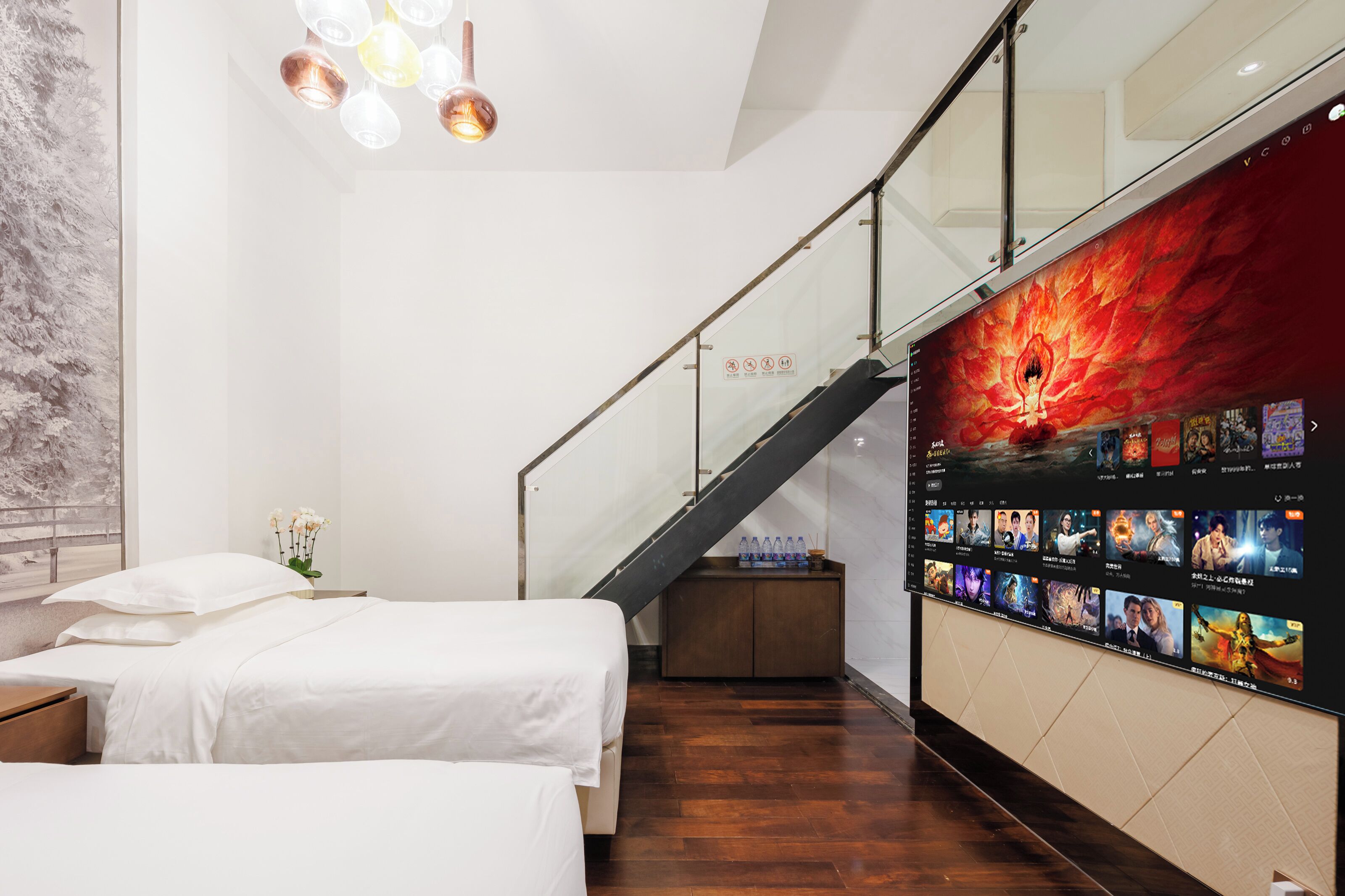 A hotel room with a bed, a nightstand, a small cabinet, and a wall-mounted TV displaying movie options.