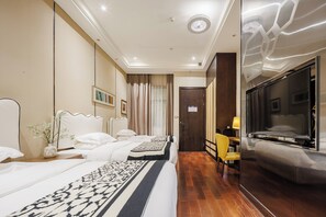 A hotel room with two beds, a desk, a chair, a TV, and a door.