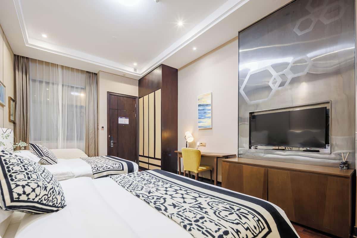 A hotel room with a large bed, a desk with a chair, a TV, and a mirror.