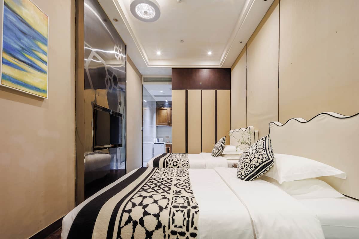 A hotel room with a large bed, a television, and a view into the kitchen area.