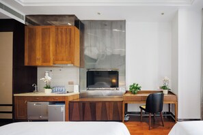 A compact hotel room with a kitchenette, a bed, a desk, and a chair.