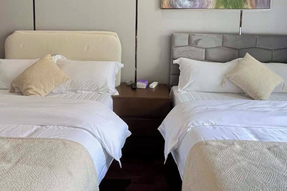 A hotel room with two beds, each with a pillow and a nightstand.