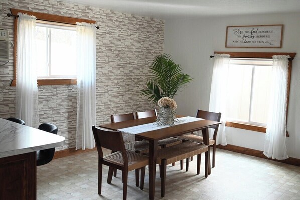 Un comedor con pared de piedra, mesa de madera, sillas y una planta en maceta.