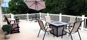 A deck with a table and chairs, a potted plant, and a large umbrella.