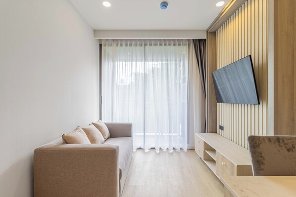 A modern living room with a sofa, a wooden TV stand, and a dining table.