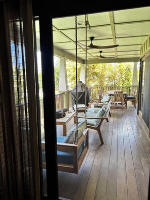 A covered outdoor seating area with wooden furniture, a ceiling fan, and a view of greenery outside. - Serene 3-bedroom home in Hanalei - TVNC 1131 (Hanalei)