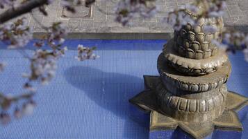 A stone fountain with a tiered design, surrounded by a blue tiled area.