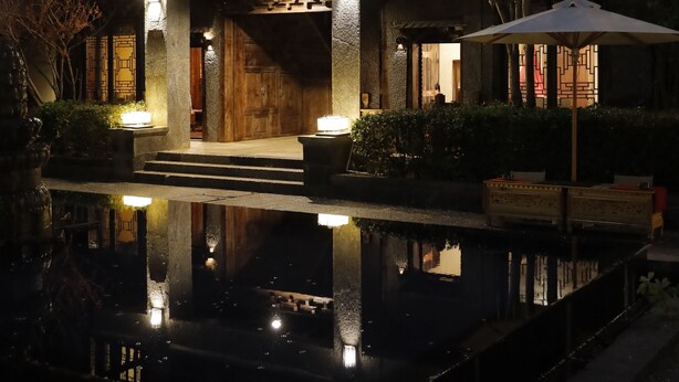 A multi-story building with a reflective pool in front, illuminated by ambient lighting. - Sangzhu Kangzhu Luxury Residence (Deqin)