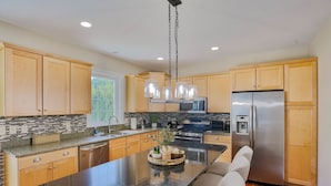 A modern kitchen with wooden cabinets, a stainless steel refrigerator, and a central island with seating.