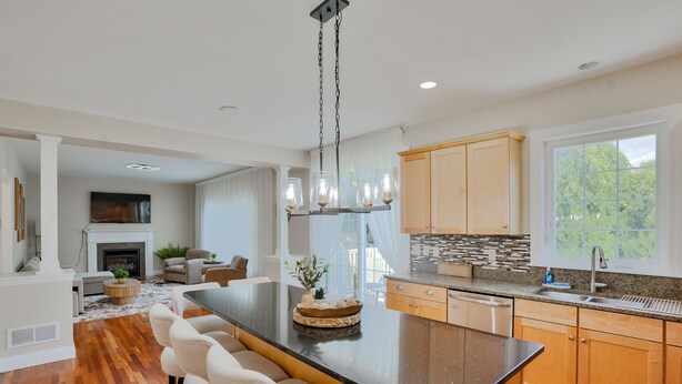A modern kitchen with a central island, wooden cabinets, and a large window.