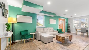 A living room with a sofa, armchairs, a coffee table, and a dining area with chairs and a table. - The Jefferson | Emerald | City View (Alexandria)