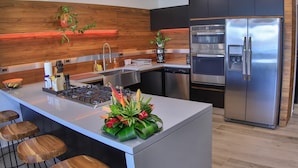Una cocina moderna con una isla central, electrodomésticos de acero inoxidable y detalles de madera.