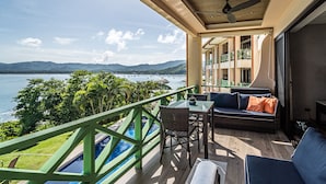 Un balcón con vistas al mar y a las montañas, una piscina y mobiliario exterior.