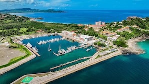 Vista aérea de un puerto deportivo con barcos amarrados, rodeado de edificios residenciales y zonas verdes.
