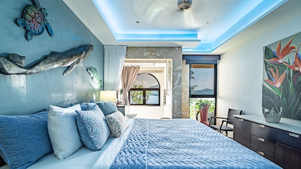 Un dormitorio con una cama grande, ventilador de techo y vistas al exterior.
