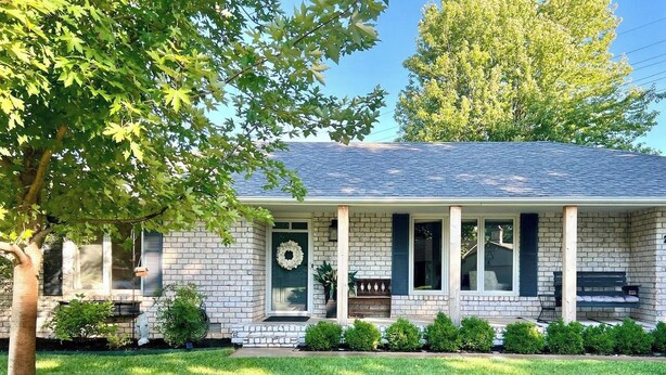 A single-story house with a brick facade, a front porch with columns, and a well-maintained lawn. - Sunlit Maple Inn-Rest Awaits You (Hutchinson)