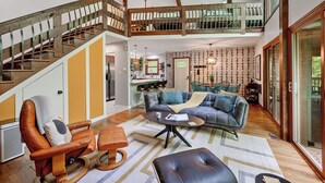 A spacious living area with a high ceiling, a wooden staircase, a sofa set, and a dining area. - Secluded Cabin Oasis Located in North Raleigh... (Raleigh)