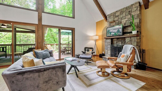 A spacious living room with a large sofa, a leather armchair, and a fireplace. - Secluded Cabin Oasis Located in North Raleigh... (Raleigh)