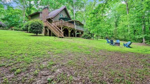 A cabin with a deck, surrounded by a grassy yard and trees. - Secluded Cabin Oasis Located in North Raleigh... (Raleigh)