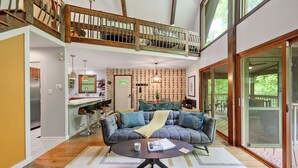 A spacious living area with a grey sofa, a round coffee table, and a high ceiling with exposed wooden beams. - Secluded Cabin Oasis Located in North Raleigh... (Raleigh)