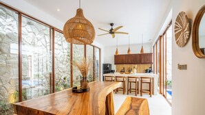 Una cocina moderna con una isla de madera, ventanas amplias y una pared de piedra.