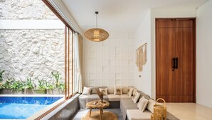 Una sala de estar moderna con una pared de piedra, un ventanal grande, una piscina y una puerta de madera.