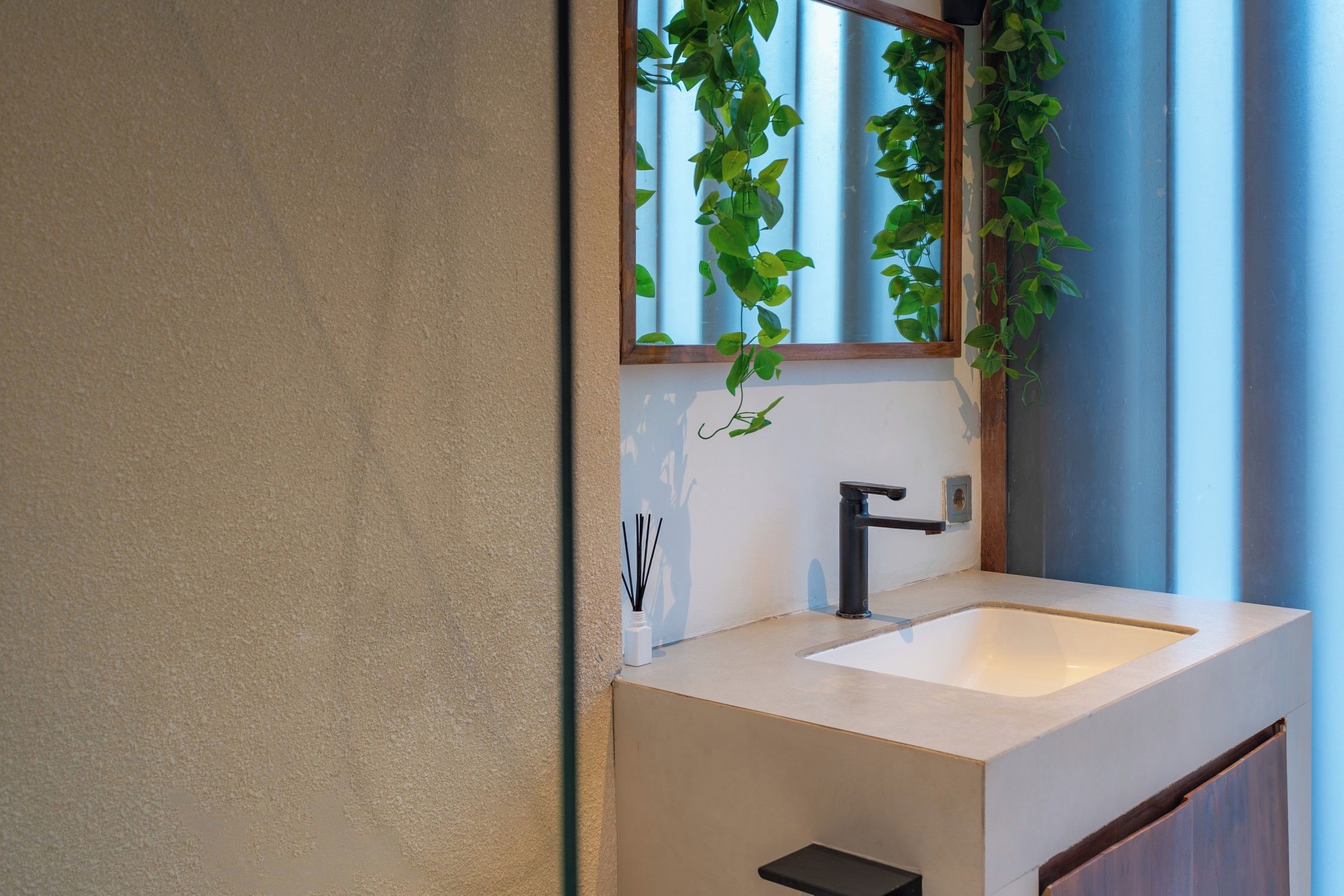 A bathroom with a white sink, a black faucet, and a mirror with a wooden frame.