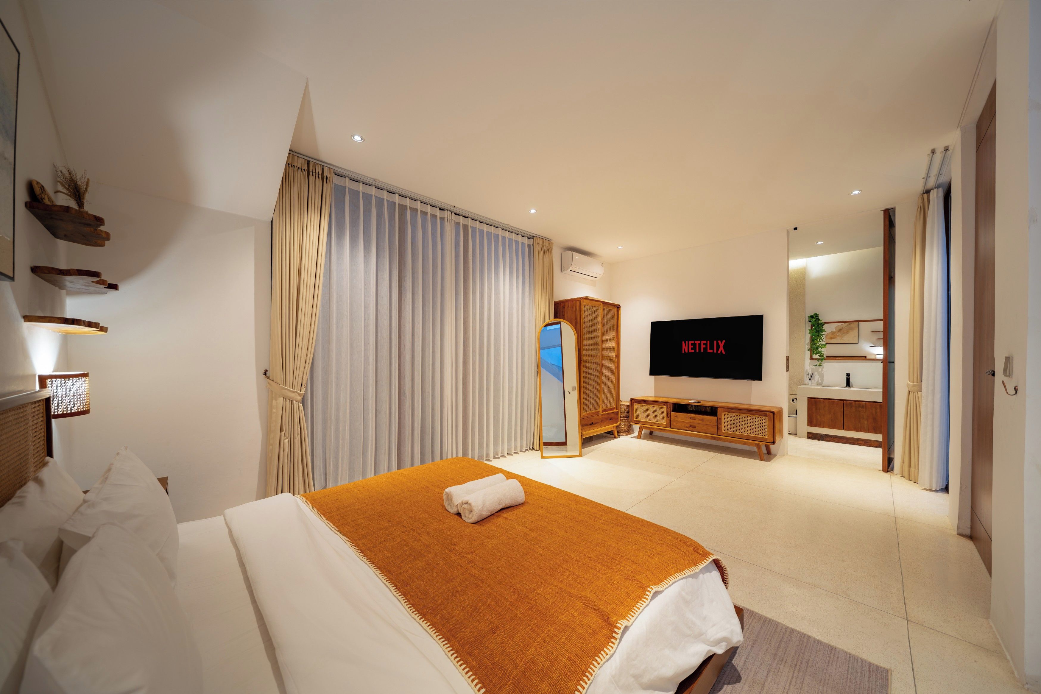 A modern hotel room with a bed, a TV, a wardrobe, and a bathroom.