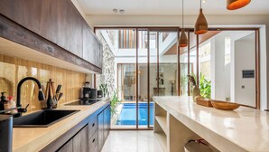 Cocina moderna con una isla grande, horno empotrado y vista a una piscina.