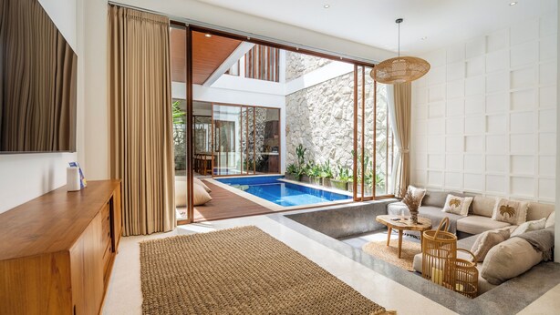 Una sala moderna con piscina, muebles de madera y una pared de piedra.