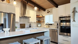 Una cocina moderna con electrodomésticos de acero inoxidable, taburetes de bar de madera y una isla grande.